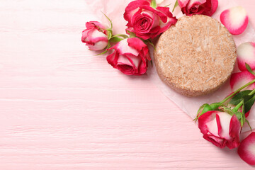 Solid shampoo bar and roses on pink wooden table, flat lay. Space for text