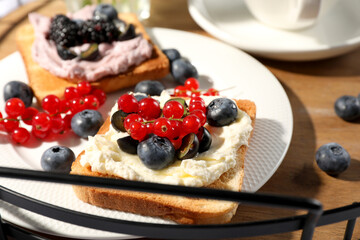 Sandwiches with cream cheese and berries on wooden tray