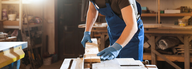 Professional carpenter working with wood in shop, closeup. Banner design