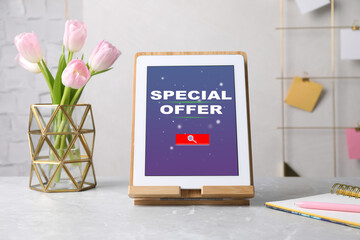 Modern tablet with phrase Special Offer, stationery and flowers on grey marble table