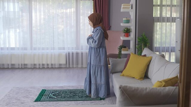Happy young muslim woman praying in islamic faith.
Believer Muslim Woman praying at home.
