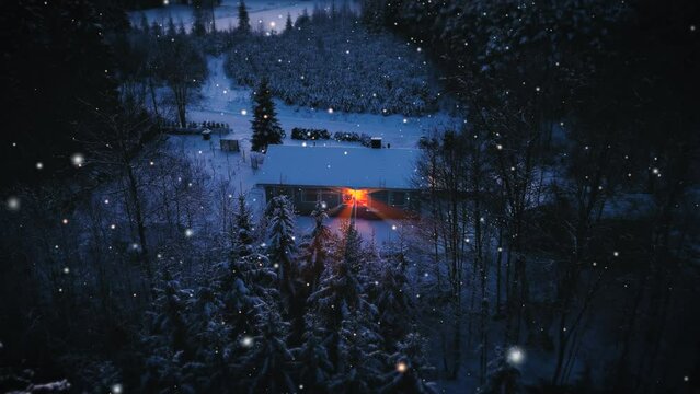 Aerial view towards a snowy house with a light inside, during snowfall on a winter evening