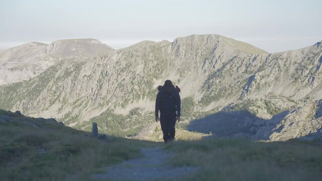 a man trekking alone in the mountains, walking towards the camera.