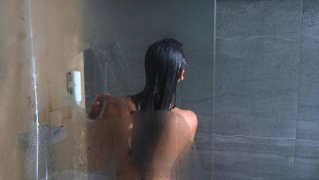 Attractive young woman washing and dancing in the shower