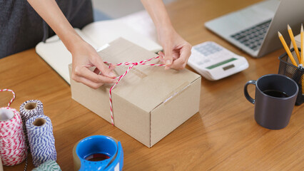 Online selling concept, Asian business women packing product into parcel box and tying with rope