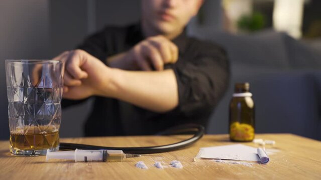 Drug addicted man is having a seizure and getting ready to put a syringe on his arm.
Problem man addicted to drugs and alcohol is hallucinating and preparing to put a syringe in his arm.
