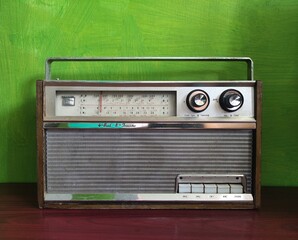 old transistor radio on wooden table green wall background