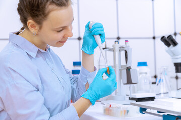 young woman laboratory assistant loads biological sample into micro test tube, microbiology...
