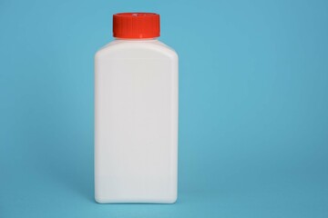 white plastic bottle with a red cap on a blue background