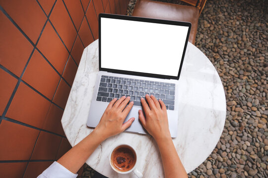 Top view mockup image of a woman using and touching on laptop touchpad with blank white desktop screen with coffee cup