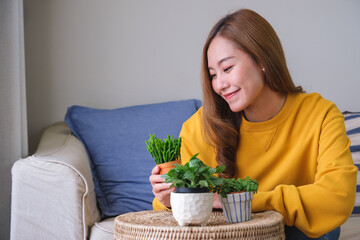 Portrait image of a beautiful young woman looking and taking care of houseplants at home