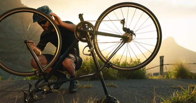 Bicycle, wheel and tyre on road with man athlete fix problem on rim outdoor in sunset. Cyclist, bike or broken in street on training, fitness and exercise ride for sport or prepare for competition