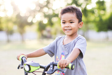 Obraz premium Happy and smiling kid boy riding a bycicle in Park