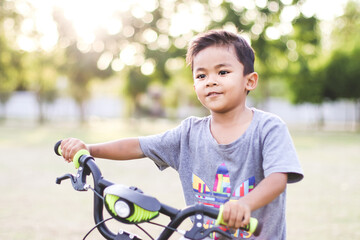 Obraz premium Happy and smiling kid boy riding a bycicle in Park