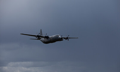 Fototapeta na wymiar military transport aircraft at low altitude with dark clouds in the background