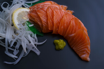 Salmon Sashimi in Japanese buffet restaurant menu.Fresh salmon fillet on black plate salmon slices.Asian people eating sashimi set Japan restaurant.salmon sashimi.Asian Food Menu.seafood sashimi.