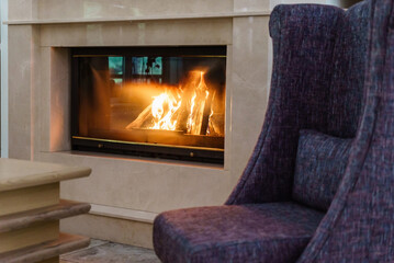 Cozy living space by the burning fireplace with chair,