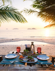 Dinner table during sunset on a beach with fish and Thai food.Romantic dinner table © Fokke Baarssen