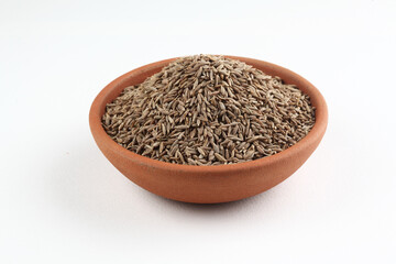 Cumin seeds in a terracotta bowl placed on a white background 