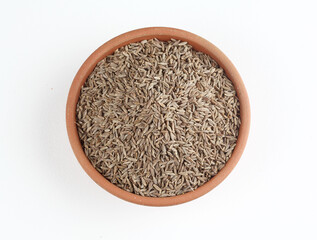 Cumin seeds in a terracotta bowl placed on a white background 