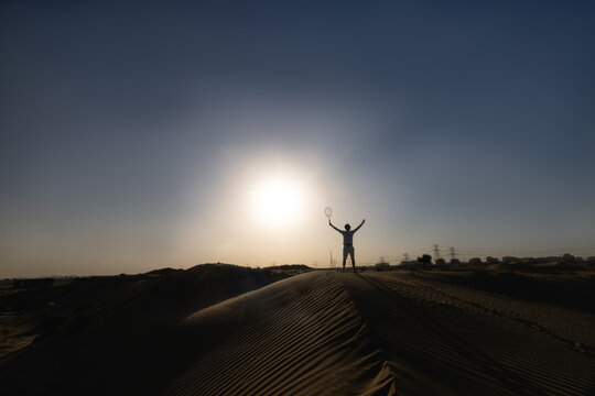 Handsome Man playing tennis on a barkhan in the desert