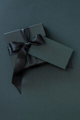 Gift box with black ribbon and empty card isolated on black Black Friday Sale.