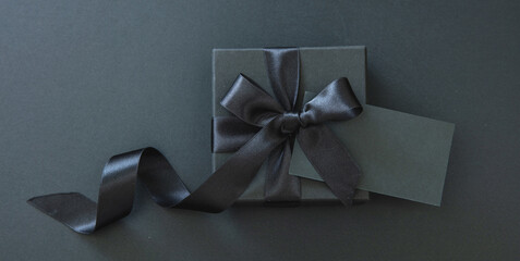 Black Friday Sale. Gift box with black ribbon and empty card isolated on black