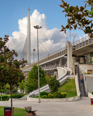 Staircase and escalator leading to the metro station in the middle of Golden Horn Metro Bridge, or Halic Bridge, with lots of green trees around, Istanbul, Turkey