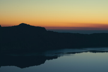 Sunset over Crater Lake National Park in Oregon, with the rim of the Crater in silhouette. 
