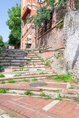 Fototapeta na wymiar Walkway with red bricks stairs leading to old traditional building and trees, in sunny day, Balat district, Istanbul, Turkey