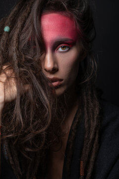 Ethnicity, tribe, make-up concept. Beautiful native American Indian woman studio portrait. Messy model hair with dreadlocks and with tribe red make-up looking to camera with seductive look