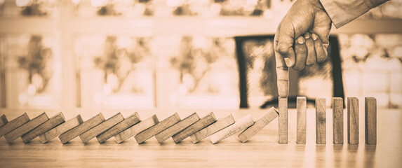 Close-up hand prevent wooden block not falling domino concepts of financial risk management and...