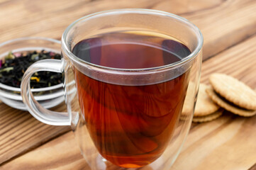 Glass cup of tea with dry tea and cookies on the table. Close up.