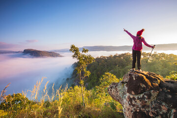Young woman in red jacket hiking on Pha Muak mountain, border of Thailand and Laos, Loei province, Thailand.
