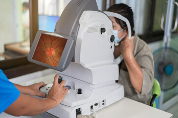 Woman looking at refractometer eye test machine in ophthalmology.Expert is taking pictures of the retina.