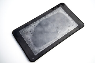 Tablet computer after getting into the water. Moisture under the smartphone screen. A damaged electronic gadget after rain on a white background.