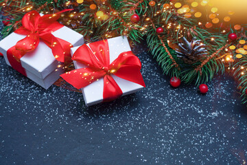   Spruce, fir branches, red berries, gift box on black stone background. Frame border. Christmas New Year composition background. Christmas lights. Space for text