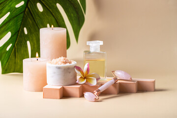 Holistic skin care still life . Natural oil bottle , salt scrab,candle, gua sha roller on beige podium with monstera leave. Wellness center and spa salon concept.Copy space