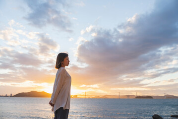 Fototapeta premium 夕暮れの海にいる女性