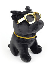 Plush soft black pug dog toy with golden sunglasses isolated on white background. Close-up. Three...