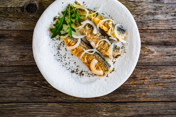 Fish dish - marinated fried herrings on wooden table
