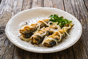 Fish dish - marinated fried herrings on wooden table
