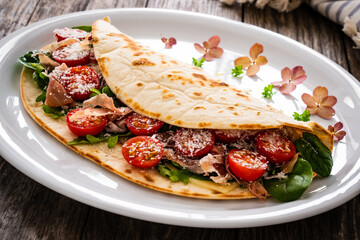 Italian piada wraps - piadina stuffed with fresh vegetable leaves, parmesan and prosciutto crudo on...