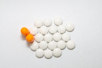 White round pills, orange capsules and ear plugs on a white background
