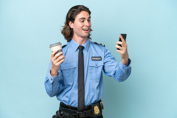 Young police caucasian man isolated on blue background holding coffee to take away and a mobile