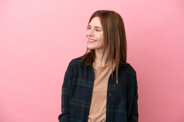 Fototapeta premium Young English woman isolated on pink background looking to the side and smiling