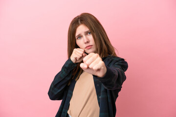 Young English woman isolated on pink background with fighting gesture