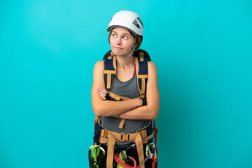 Young English rock climber woman isolated on blue background making doubts gesture while lifting the shoulders