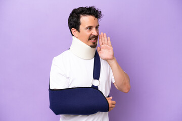 Young caucasian man wearing a sling and neck brace isolated on purple background shouting with...