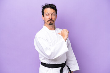 Young caucasian man doing karate isolated on purple background proud and self-satisfied
